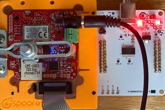 A 3D-printed pogo-pin programming fixture flashing a Spoores board